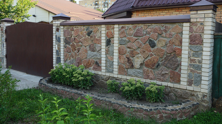 Natural stone and brick wall in a backyard surrounded by greenery