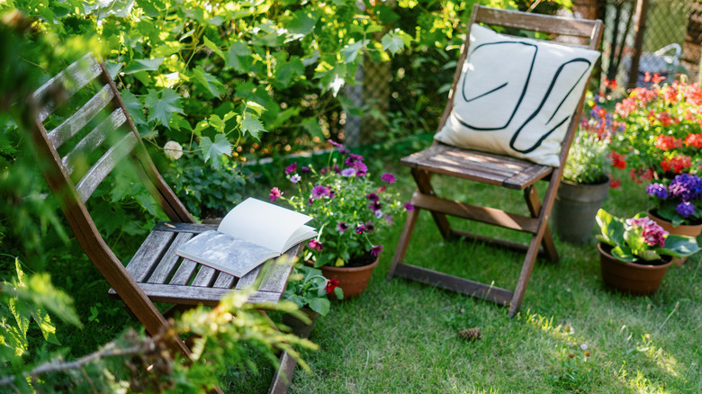 Two wooden chairs surrounded by plants and greenery