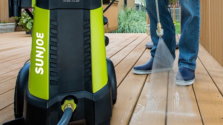 person pressure washing deck