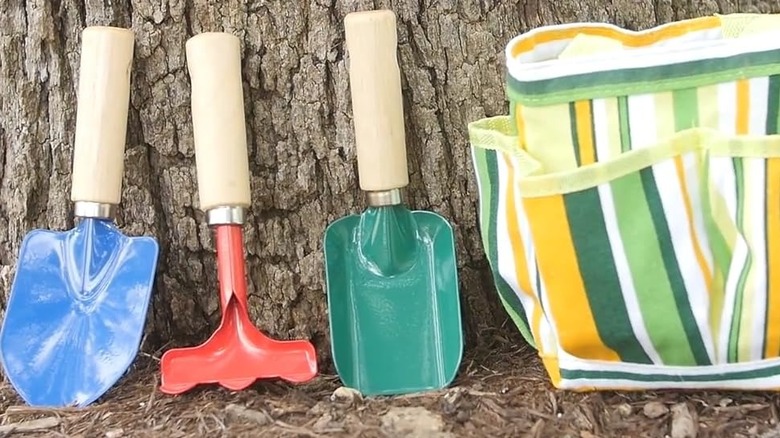 A colorful garden tool set for kids including three tools and a carry bag.