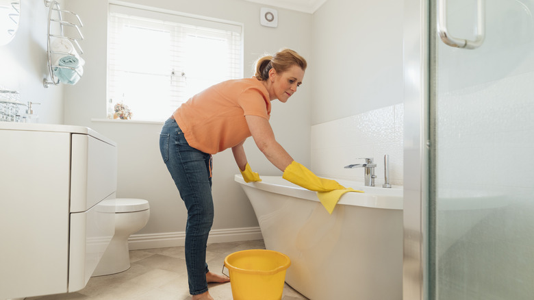Woman cleaning porcelain bathtub