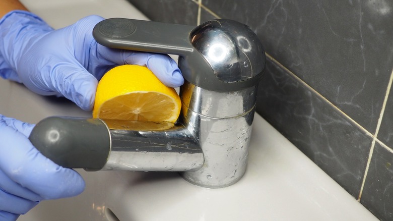 Scrubbing a faucet with lemon