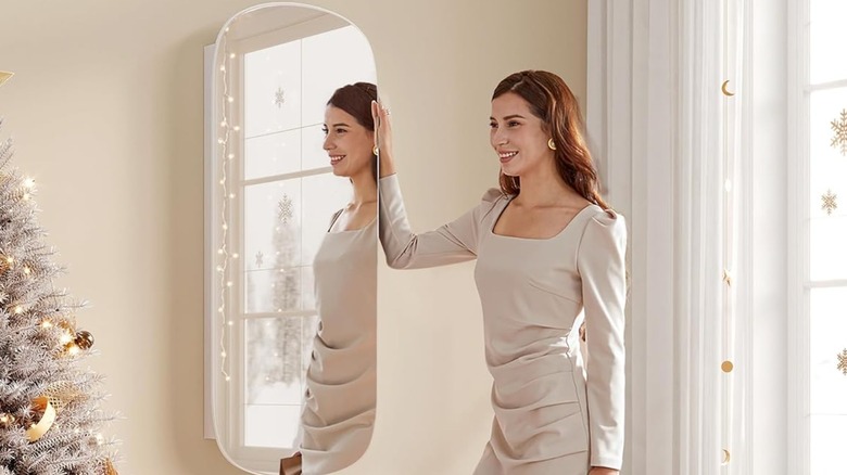 A woman standing in front of a mirrored jewelry cabinet