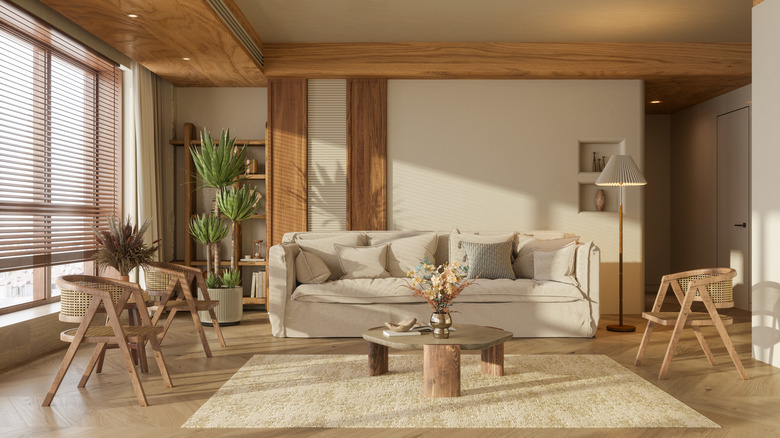 A living room with cream painted walls and wooden pieces of furniture and cream couch.