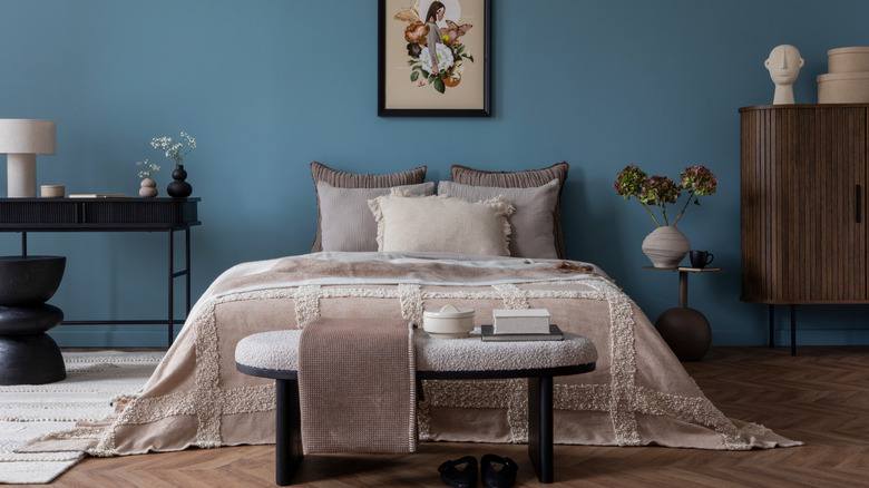 A bedroom with blue painted walls and taupe and brown colored decor/