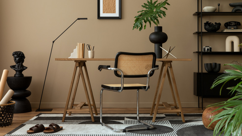 An office space with wooden and brown colored furniture, black decor, and khaki painted walls.