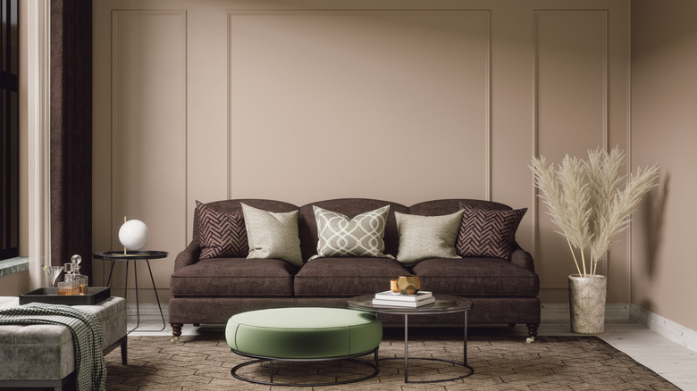 A room with wainscoted taupe-painted walls, a brown couch, and rug.