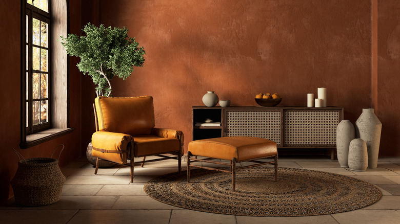 A sitting room with stylized painted terracotta walls and mid-century modern, brown furniture.