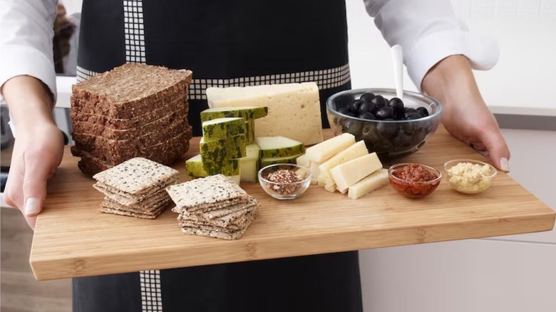 person holding bamboo cutting board with food