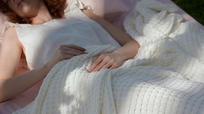 woman sleeping under white bamboo-derived blanket