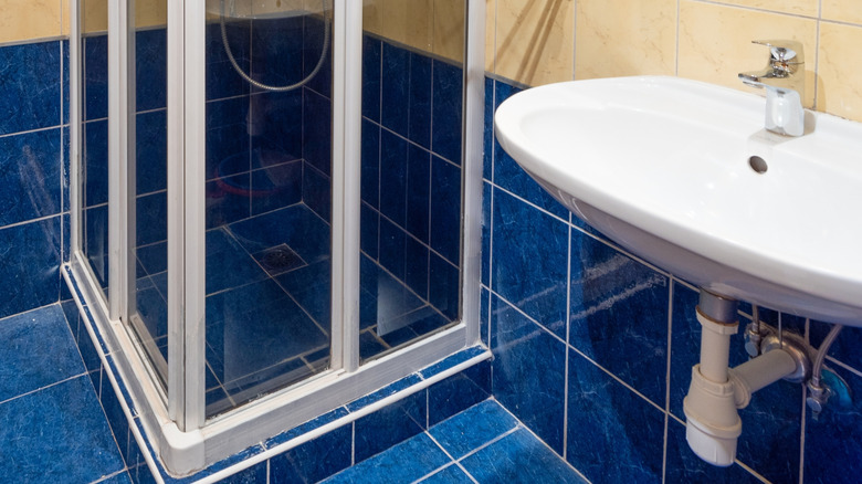 Deep blue tiles on bathroom floor under shower and sink