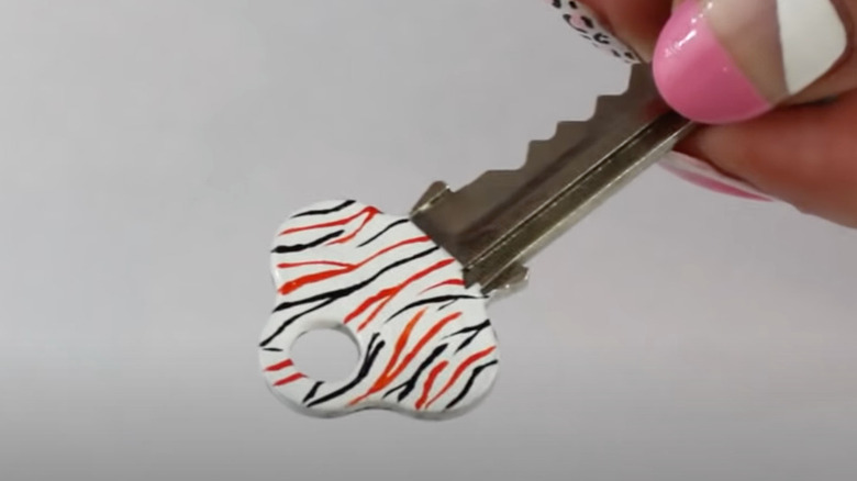 A key painted with nail polish in white, black, and orange