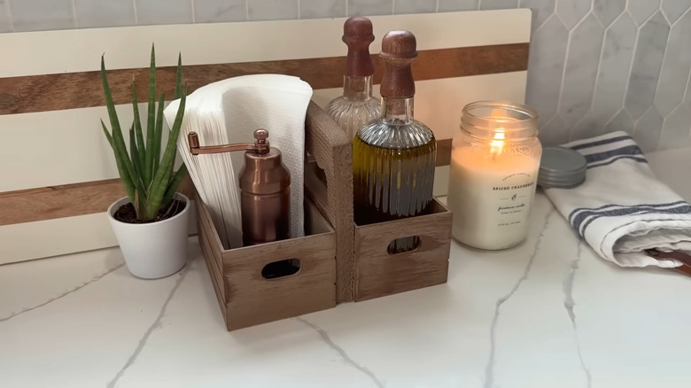 Wooden crate kitchen organizer next to lit spiced cashmere candle and snake plant