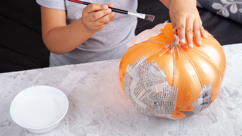 child making papier-mâché pumpkin