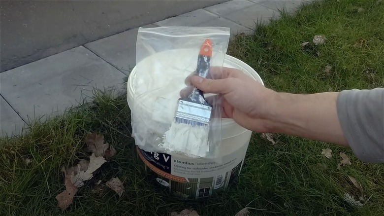 man holding paintbrush in bag