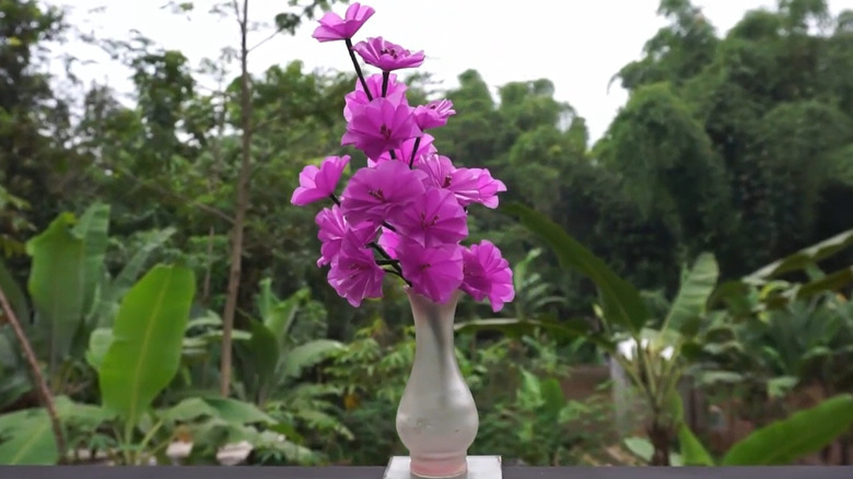 Fuchsia flowers made from plastic bags in a vase outdoors