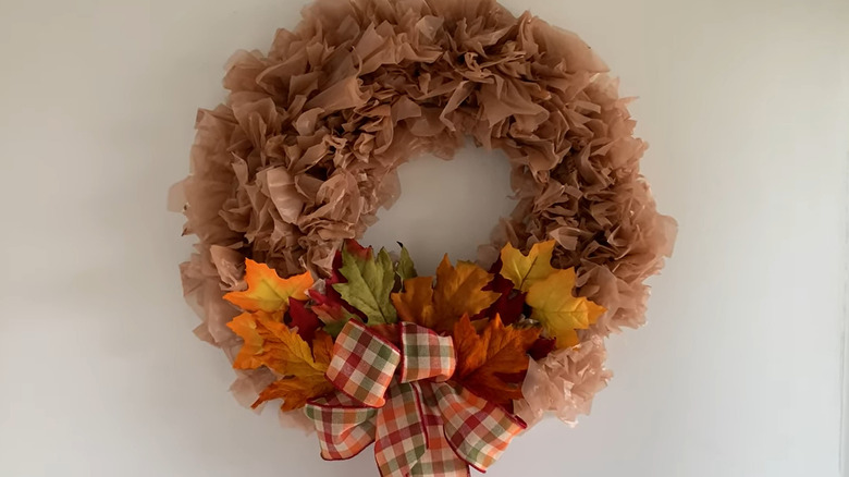 Fall wreath made from grocery bags decorated with ribbon and leaves