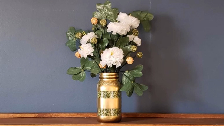 Painted mason jar filled with St Patricks day-themed flowers and clover made from plastic bags