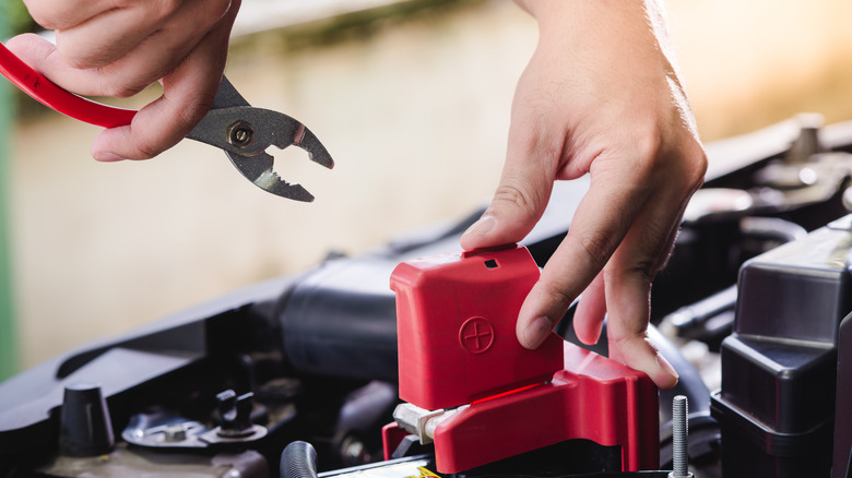 checking car engine with battery plier