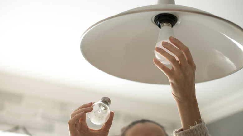 person putting in LED lightbulb