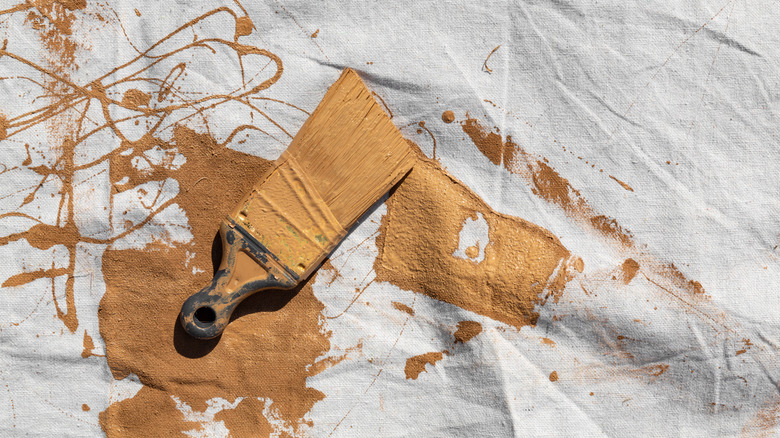 Painting tarp with brown paint and brush