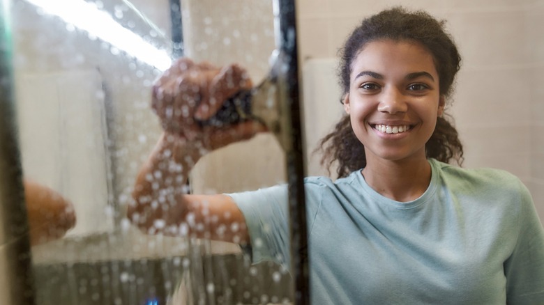 Smiling woman squeegee-ing shower