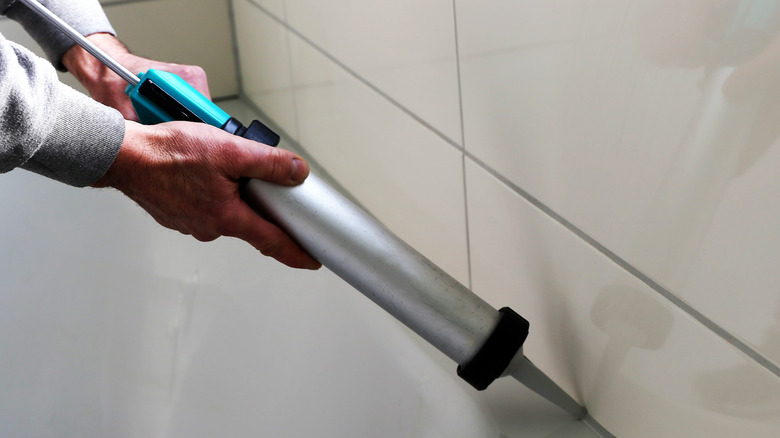 Man caulking seams in tub