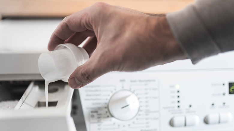 Hand pouring liquid into dispenser