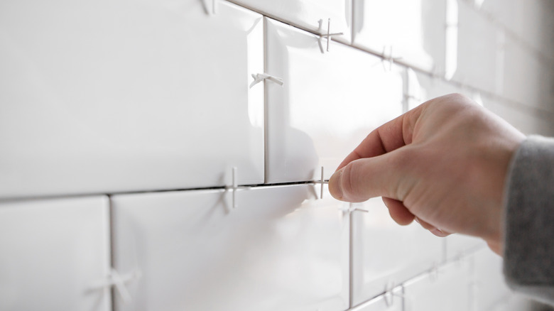 A hand removing tile spacers