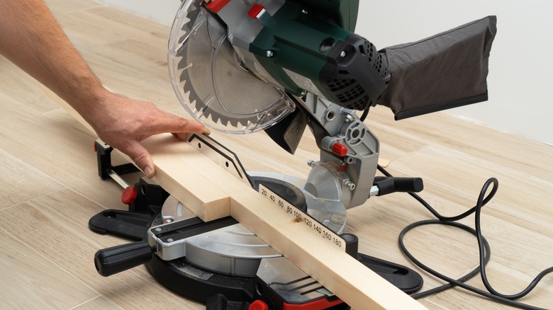 man holding wood on miter saw