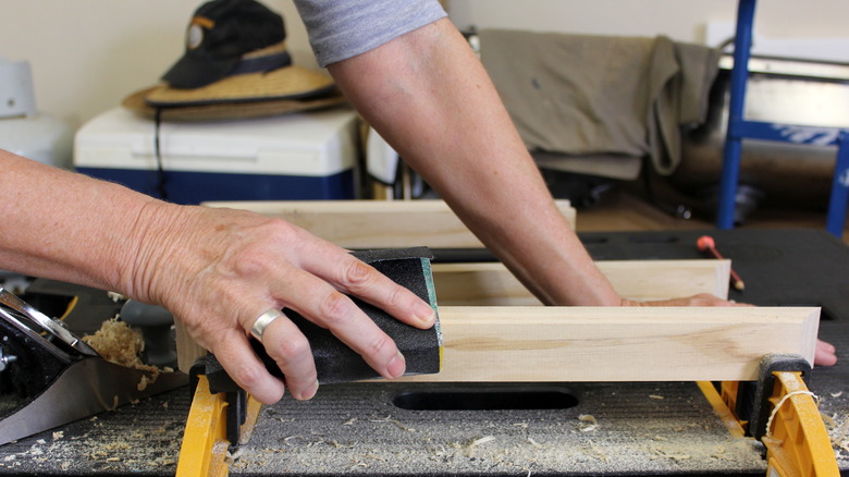 person sanding workpiece close-up