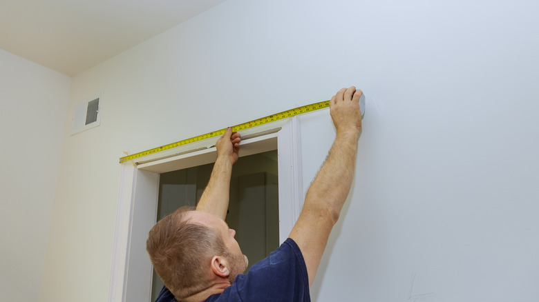 carpenter measuring mouldings on door