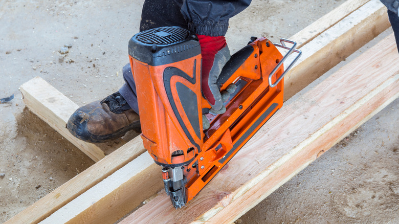 man driving nailer into wood