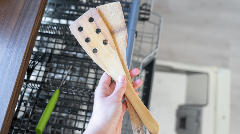 person holding old wooden spatulas