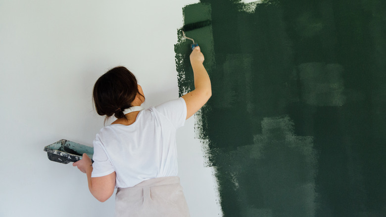 Woman rolling paint on wall