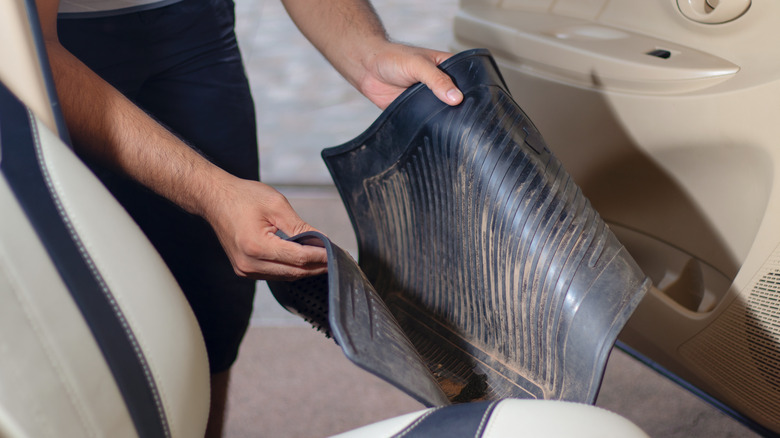 Man lifting dirty floor mats