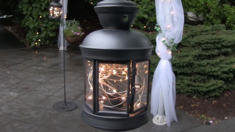 Black lantern hanging outside filled with twinkle lights