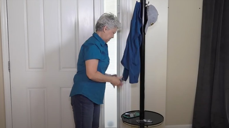 Woman leaving jacket and keys on floor lamp turned into coat rack