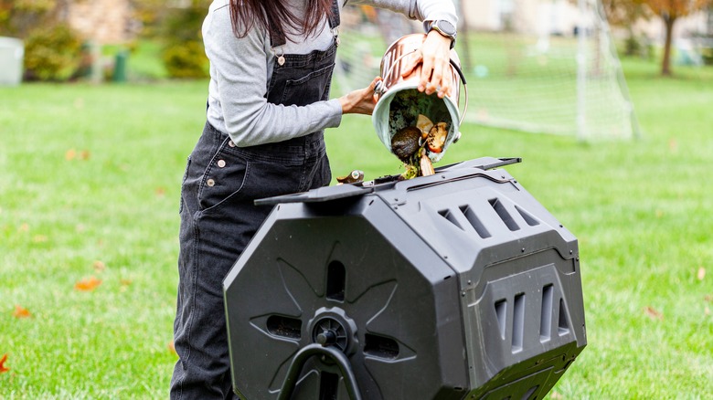 A person dumping compost into a tumbler