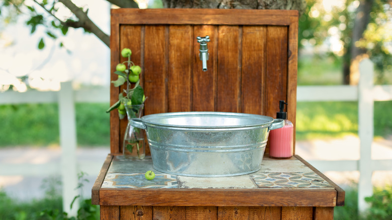 A DIY outdoor sink is shown in a garden