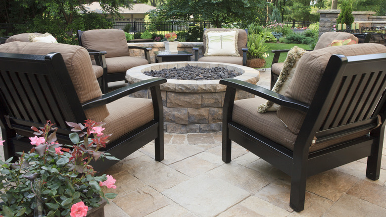 Cushioned chairs surround a stone fire pit