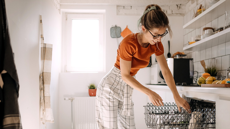 Smiling woman packing dishwasher