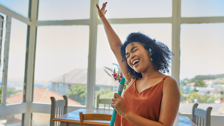 Woman singing while holding mop