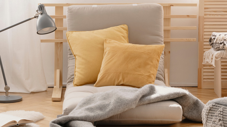 Tan futon cushion on floor