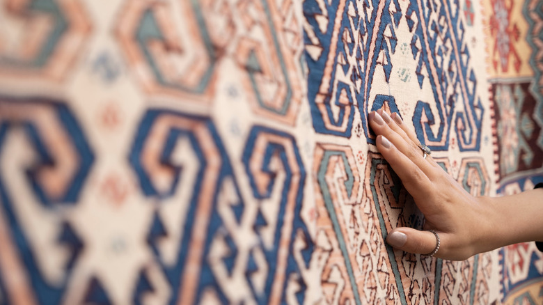 woman's hand touching rug