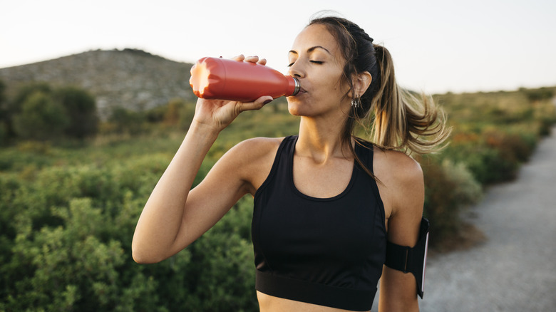 A woman stopping to drink water during a run