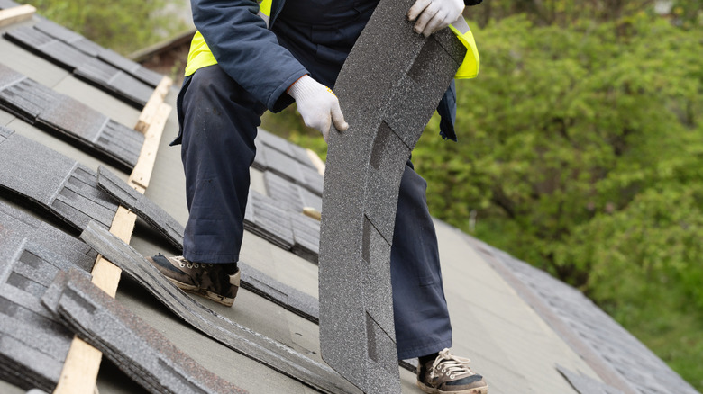 Roofer installing asphalt composite shingles