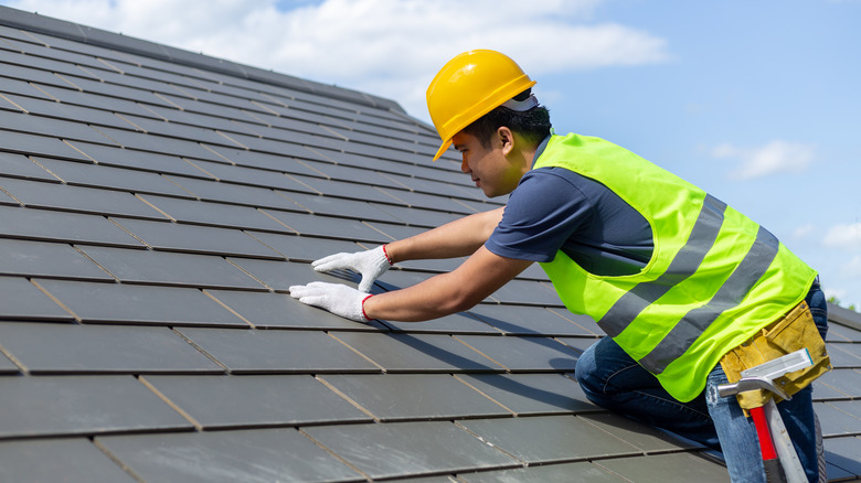 Roofer repairing slate roof tiles