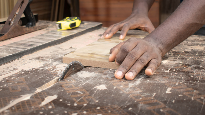 man's hands using table saw