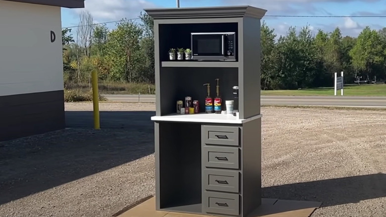 An armoire with microwave and coffee supplies